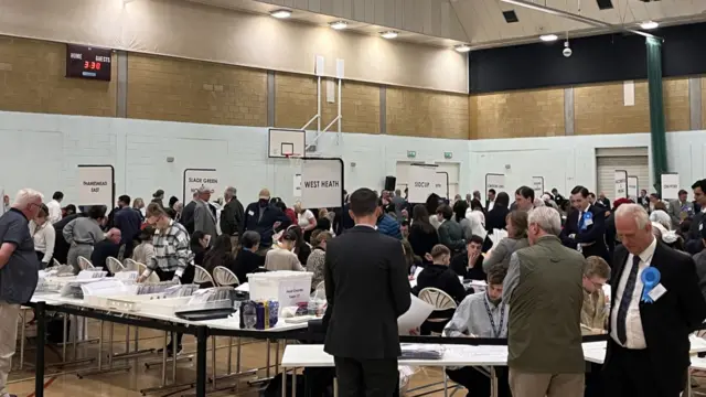 People sitting at tables and standing nearby inside a leisure centre