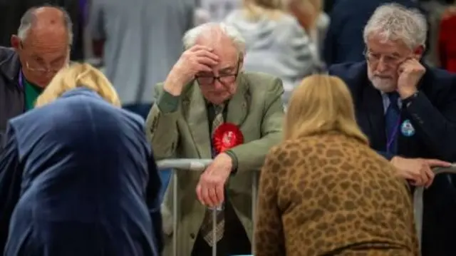 A labour member rests his head on his hand, looking down to the floor