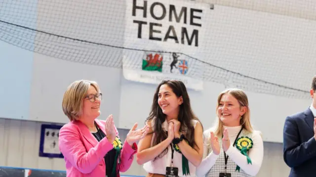 Three Plaid Cymru candidates are smiling and clapping with eachother