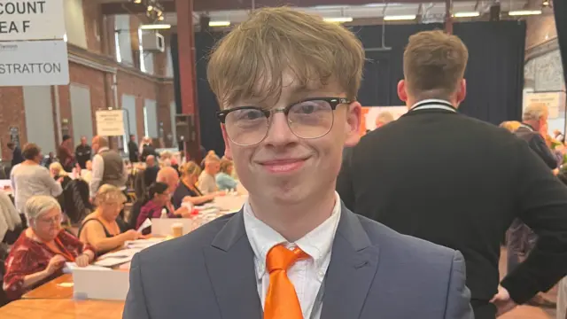 Calum wearing a suit with an orange tie.