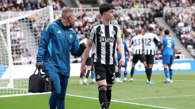 Tino Livramento of Newcastle United walks of the pitch with medical staff after an injury
