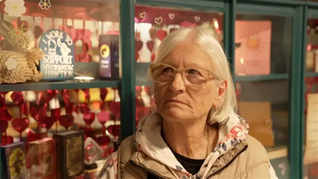 A woman in a cream top looks at the camera