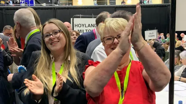 Two women clap and smile at election count in Barnsley