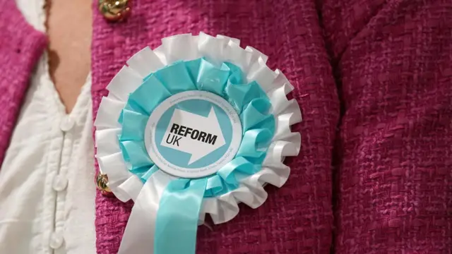 A Reform UK candidate wears a party rosette during the 2026 Essex County Council election at Clacton Leisure Centre in Essex.