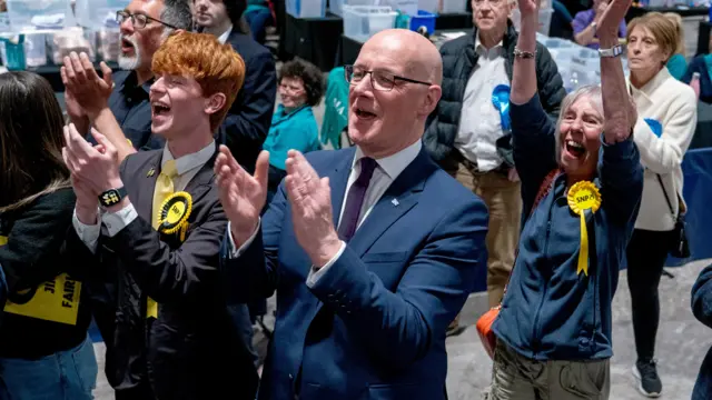 John Swinney claps his hands with other SNP supporters in Perth