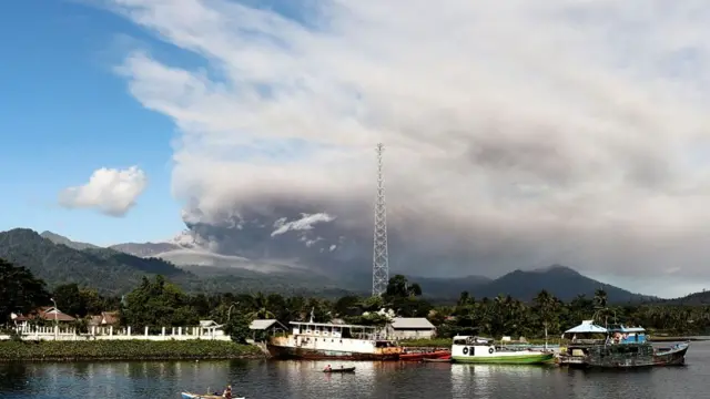 The volcano seen behind a body of water and ships