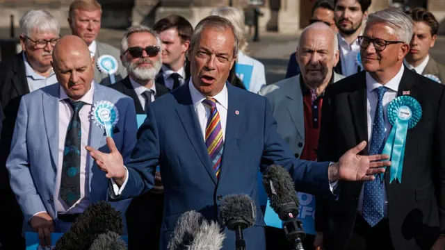 Nigel Farage stands in front of a group of people