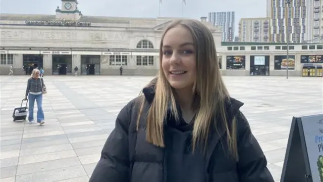 Amelia stands outside a train station in Cardiff