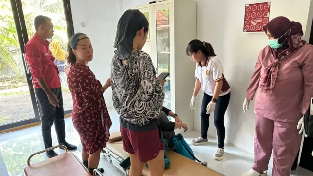 People in a room surrounding a stretcher
