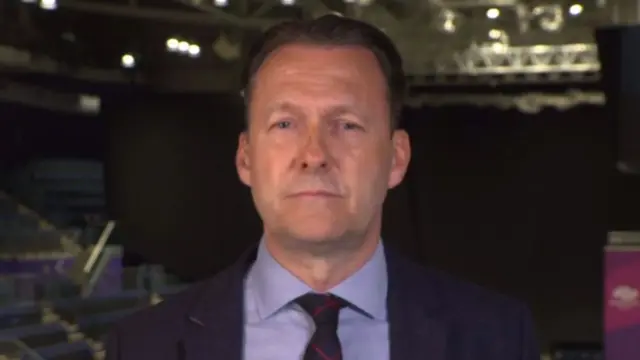 Russell Findlay has dark hair and is wearing a dark blue suit at a vote count