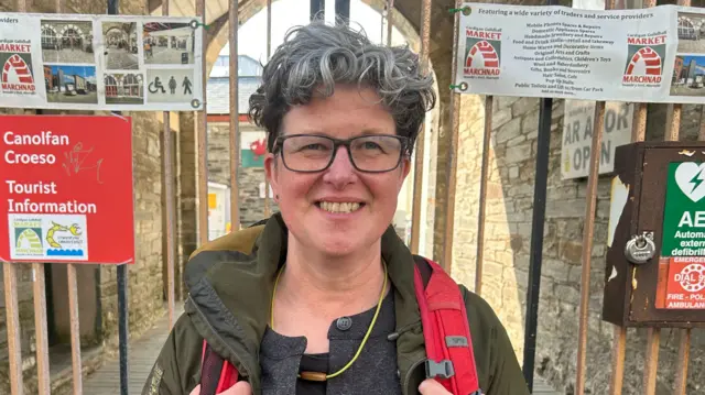 Anne Cakebread is wearing a backpack and is smiling at the camera.