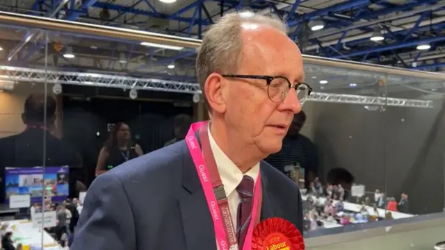 Sir Stephen Houghton, who has receding hair and glasses, speaks to a reporter