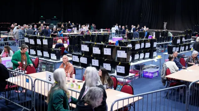 Ballot boxes are stacked on tables ahead of the count for the 2026 Senedd elections at The Arena, Venue Cymru, Llandudno