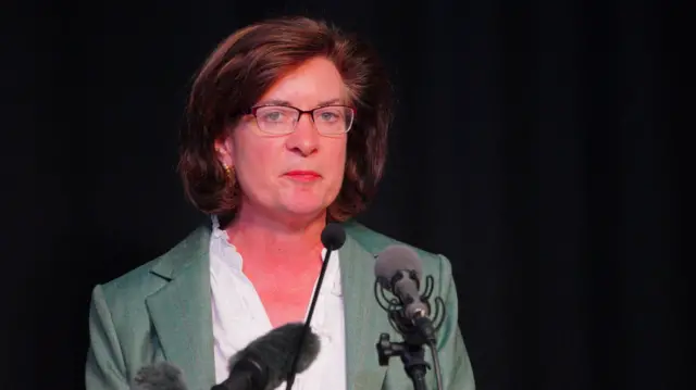 Welsh first minister Eluned Morgan mid-speech as she announces her resignation. She's wearing a sage green suit and white shirt