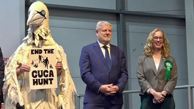 Wildlife campaigner and election candidate Robert Pownall, dressed as a gannet, stands next to the SNP's Angus Robertson and successful Scottish Green Party candidate Lorna Slater as they listen to the constituency results being declared for Edinburgh Central