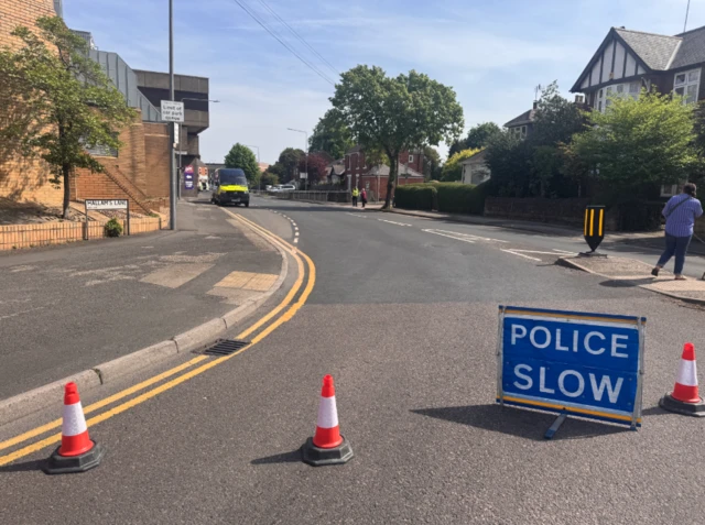 Cones and a "Police Slow" sign with a police van in the background
