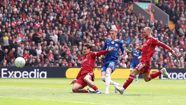 Cole Palmer goes for goal between two Liverpool players