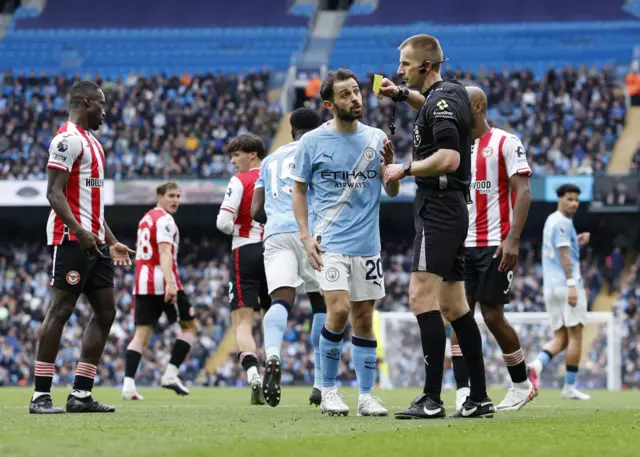 Bernardo Silva is shown a yellow card by referee Michael Salisbury