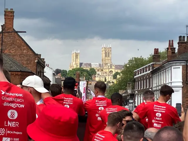 The players on the bus have their backs to the camera and the focus is up the hill on the Cathedral.