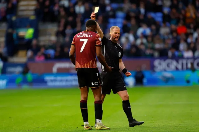 Josh Neufville of Bradford City is shown a yellow card by referee Martin Coy