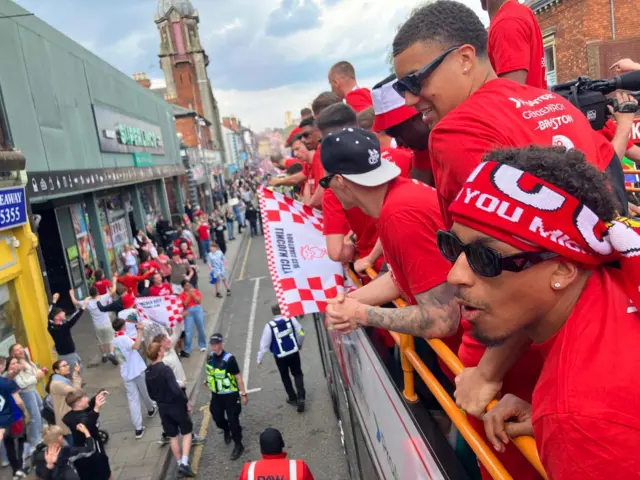A view from the top of the bus with the players and crowds below on the street.