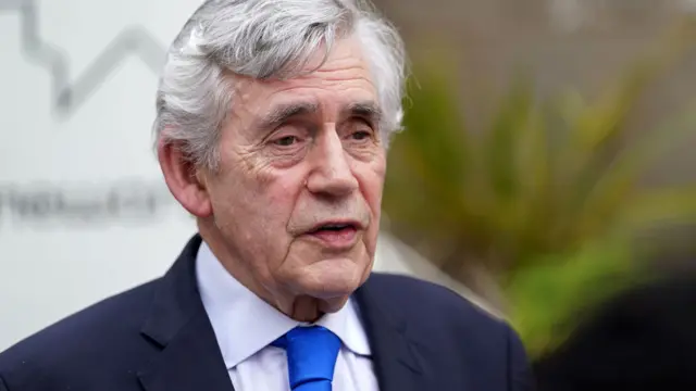 Former PM Gordon Brown pictured wearing navy suit and electric blue tie