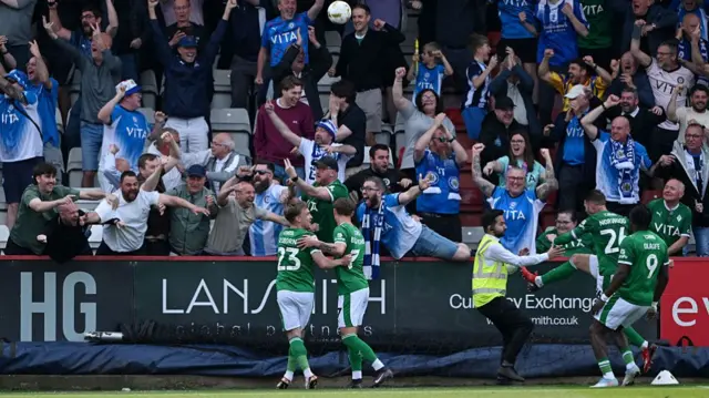 Ben Osborn of Stockport County celebrates scoring his team's first goal with fans and teammates