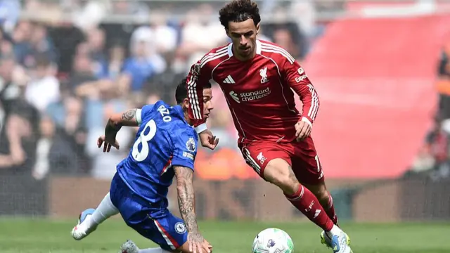 A liverpool player leads the charge for the ball past a Chelsea player