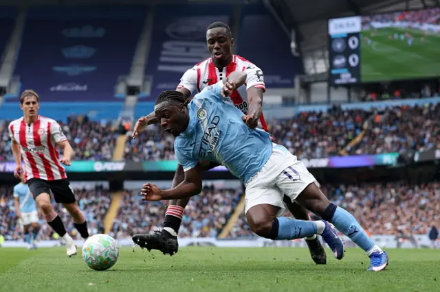 Jeremy Doku of Manchester City is challenged by Michael Kayode of Brentford