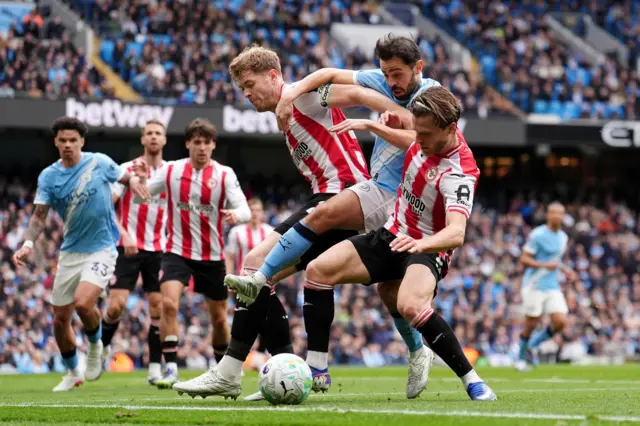 Bernardo Silva (centre) battles for the ball with Brentford's Mathias Jensen (right) and Nathan Collins