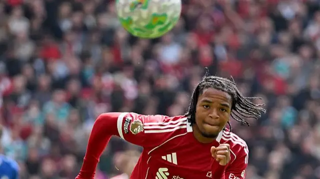Rio Ngumoah chases the ball dressed in full red Liverpool kit and a long sleeve red top under his shirt