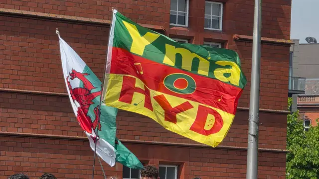 A flag that says Yma o Hyd in front of a Welsh flag
