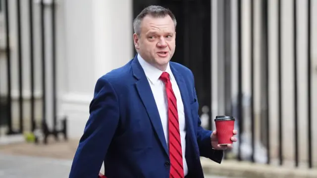 Thomas-symonds walks with a coffee in hand
