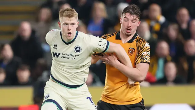 Millwall's Josh Coburn (left) and Hull City's Charlie Hughes battle for the ball during the play-off semi-final first leg on Friday