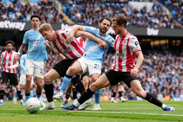 Bernardo Silva (centre) battles for the ball with Brentford's Mathias Jensen (right) and Nathan Collins
