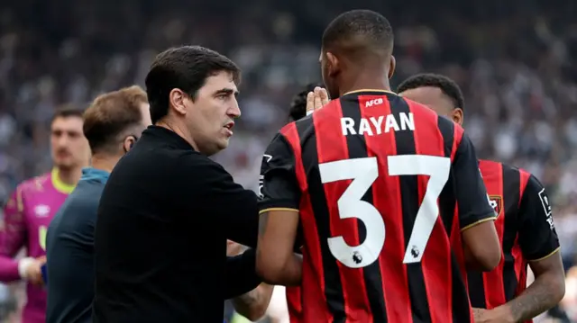 Rayan with Ireola talking, Rayan in a black and red striped Bournemouth shirt