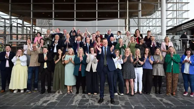 All the Plaid Cymru MS' stand clapping on the Senedd steps