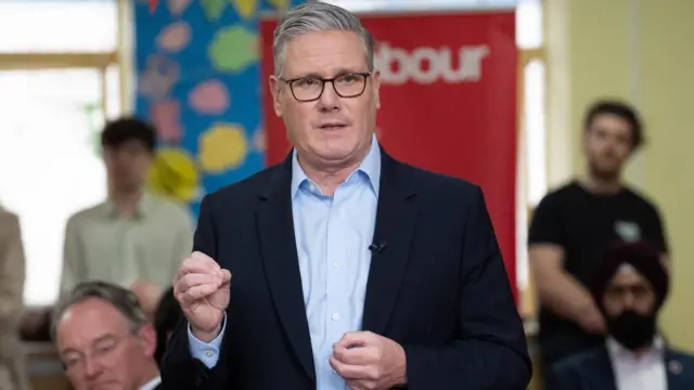 Sir Keir Starmer gestures with his right hand in a speech at Kingsdown Methodist Church Hall in Ealing,