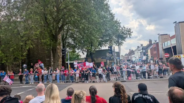 Fans stand behind barriors at the bottom of the High Street.