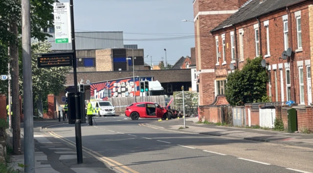 A red car with significant damage to its bonnet