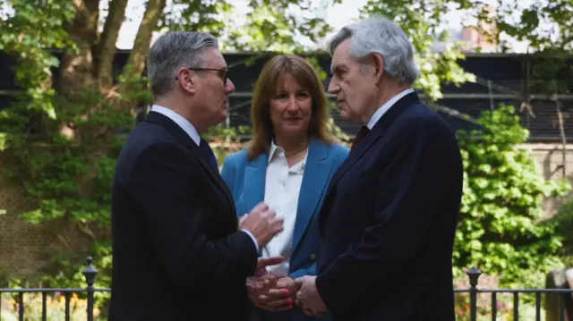 Prime Minister Keir Starmer (L), Chancellor Rachel Reeves (C) and former PM Gordon Brown (R) stand together while talking in the back garden of 10 Downing Street