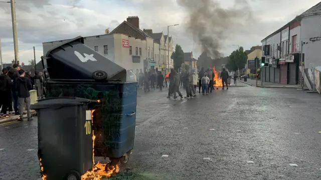 A number of youths near burning bins