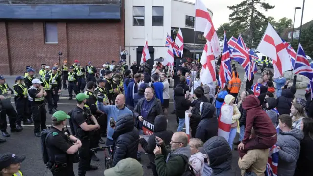 Protestors carrying Union flags and St George's flags facing a wall of police