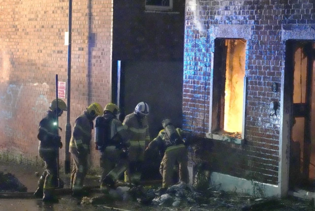 Firefighters in Northern Ireland tackling a fire inside a brick house in Belfast during the evening