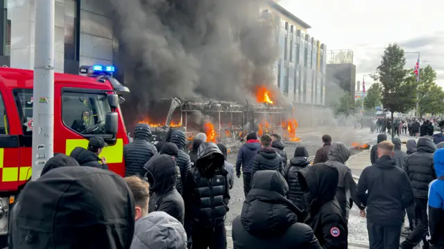 Emergency services attend to a Glider bus, set on fire by protesters, on the Newtownards Road in east Belfast.