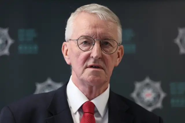 Close up of Northern Ireland secretary Hilary Benn in black suit, red tie and white shirt