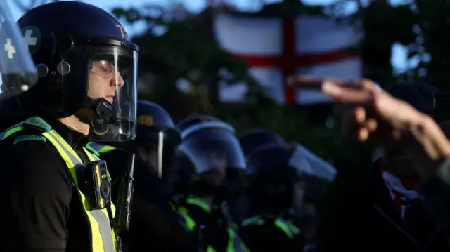 A police officer stands guard as a protester points at him with their finger during a demonstration