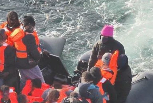 Alnour Mohamed Ali, 26, in a pink hat on board a small boat packed with people in the Channel.