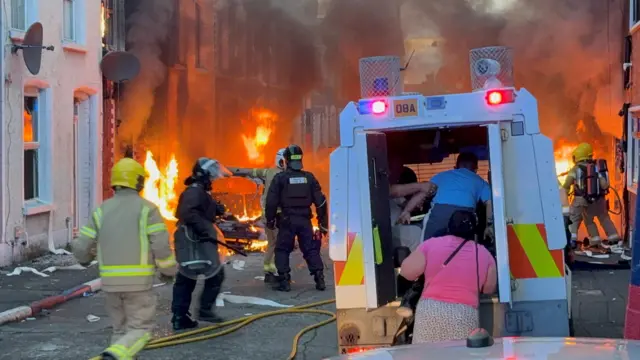 A family get into a PSNI vehicle after being rescued from houses which caught fire in Lendrick Street.