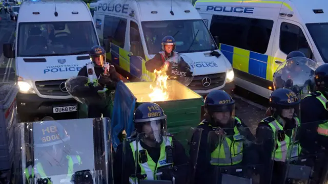 Riot police at protest with bin on fire